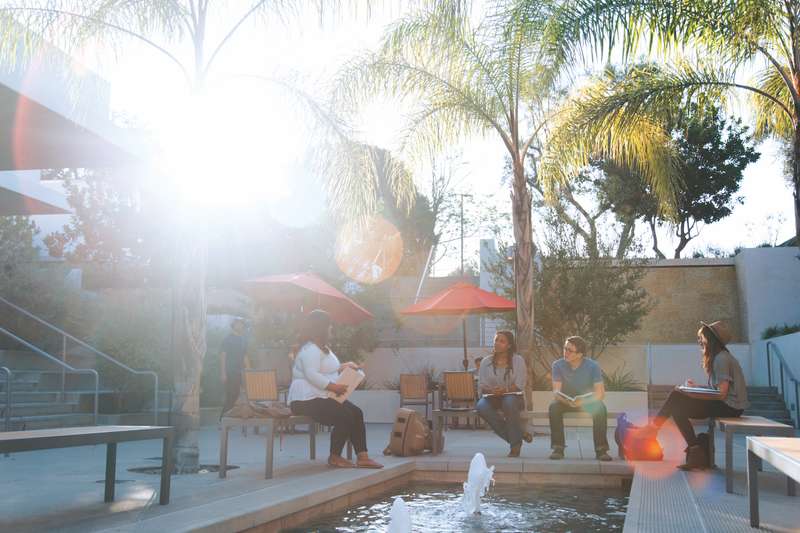 A group of students gathered around the Haqq Plaza water feature