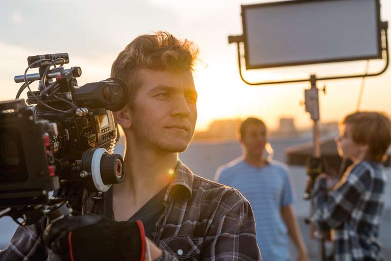 Student holds a cinema camera rig at sunset