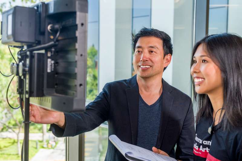 A professor watches a monitor with a student